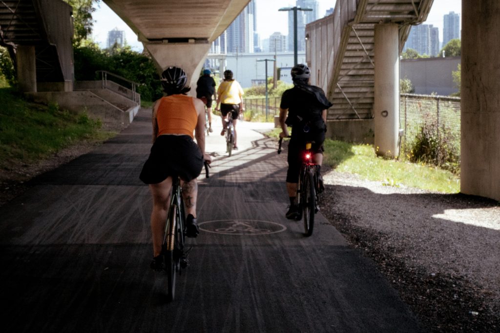 A group of cyclists ride during a summer day underneath a bridge