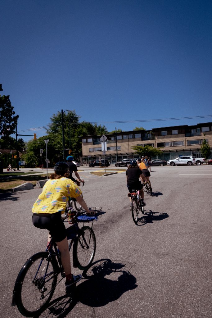 A group of cyclists ride under a blue sky on the street during a cycling event.