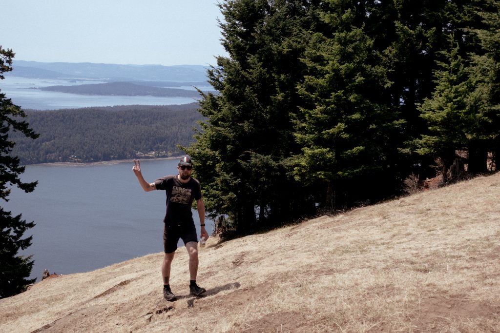 A cyclist gives the peace sign above a vista showing the Gulf Islands