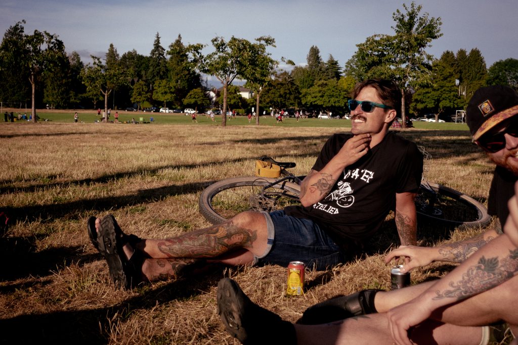 A cyclist wearing sunglasses scratches his chin.