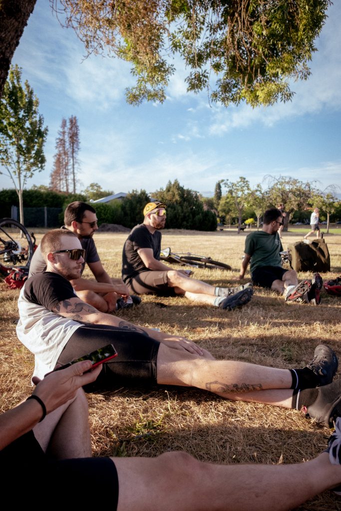 A group of 5cyclists sit on the grass. on a summer day