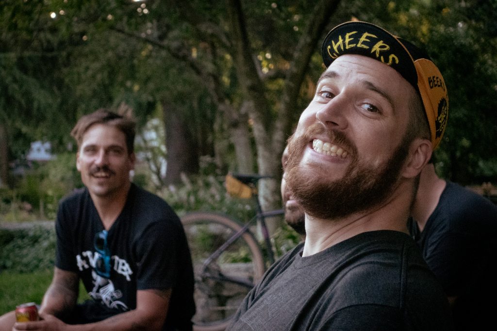 A cyclist smiles towards the camera, with another laughing in the background.