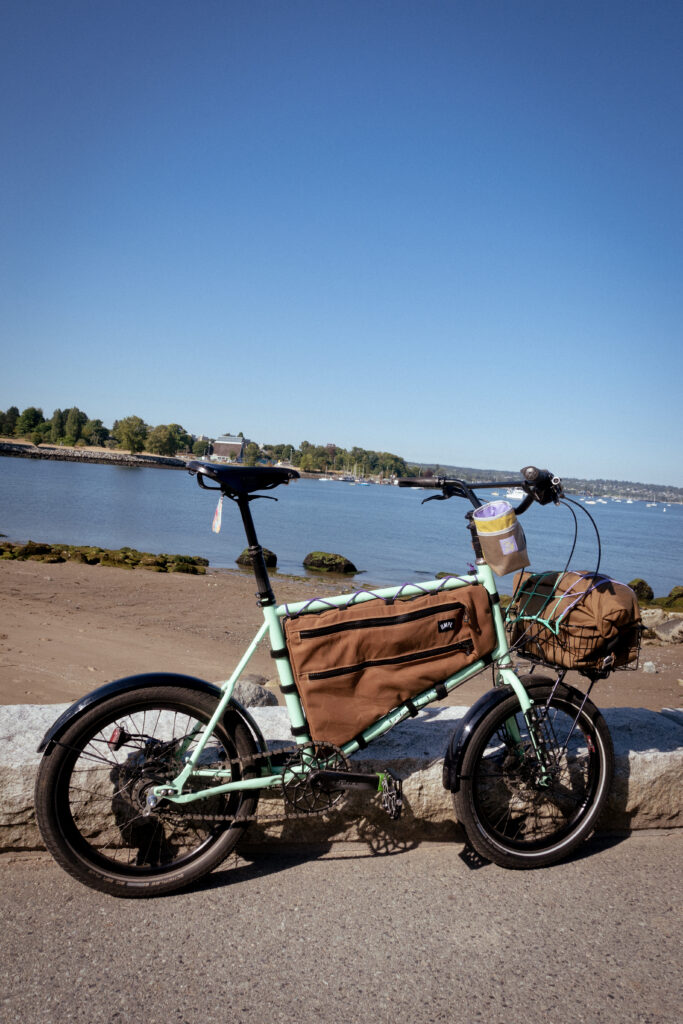 A Velo Orange Neutrino bicycle leans against a crub in front of a beach in Vancouver BC