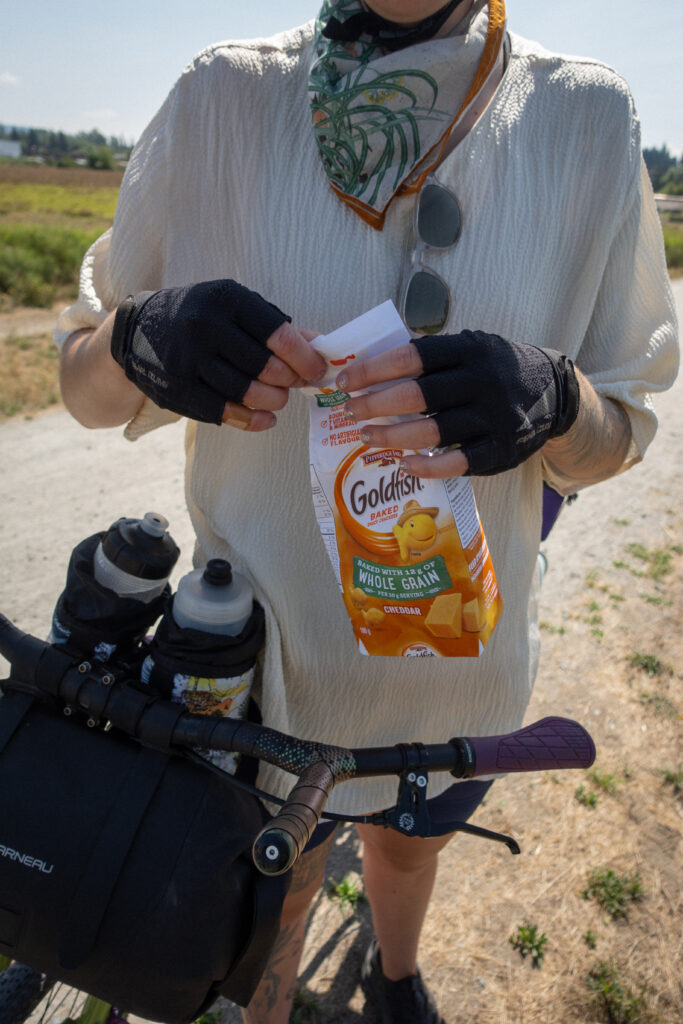 A bike rider holds a pack of Goldfish snack.