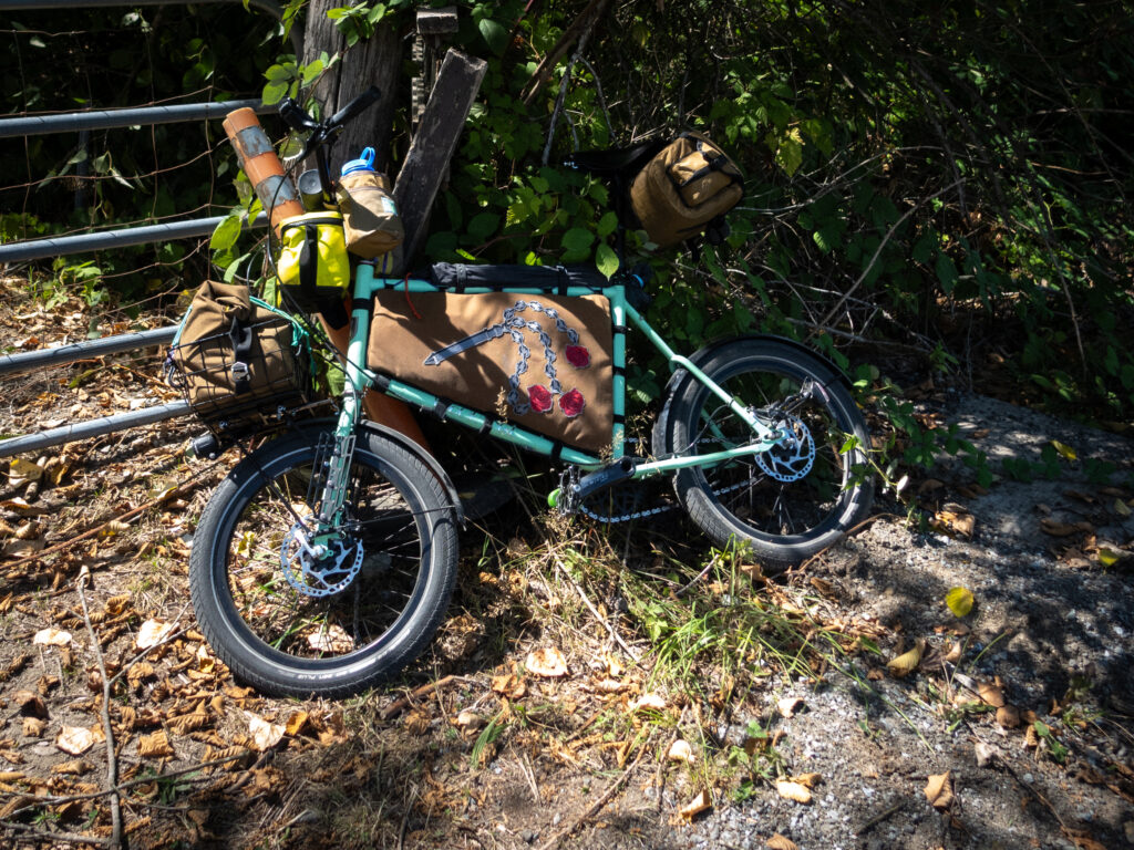 A small Velo Orange Neutrio bicycle lays against a farm gate. It is a small 20 inch wheeled bike