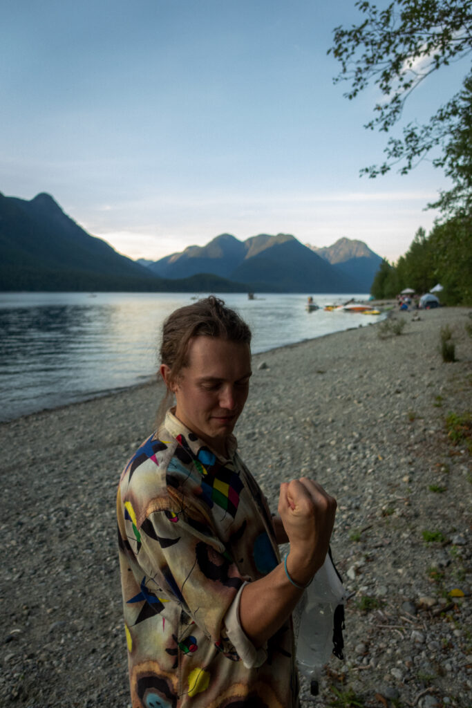 A man in a colourful shirt flexes his muscles on the beach