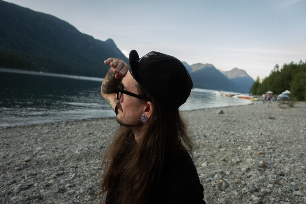 A cyclist looks off into the distance on a beach wearing a cycling cap.